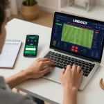 Person engaging with cm88 online sports betting platform using laptop and smartphone for strategic gameplay.